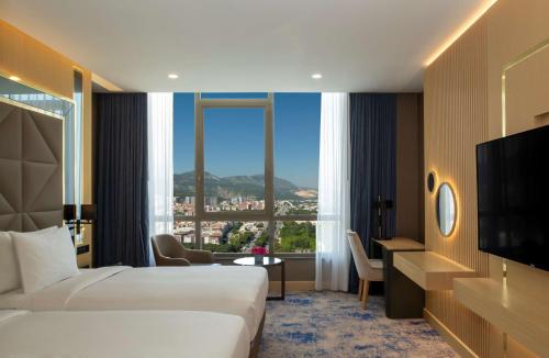 马尼萨DoubleTree by Hilton Manisa的酒店客房设有两张床和大窗户。