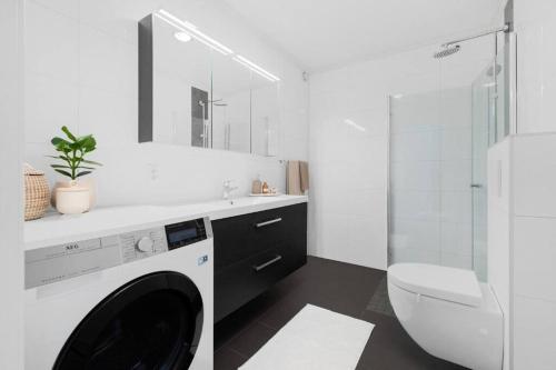 特隆赫姆Bakklandets Perle 3-roms的白色的浴室设有洗衣机和卫生间。