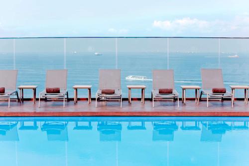 伊斯坦布尔伊斯坦布尔莫达希尔顿逸林酒店 的一组椅子和桌子,位于游泳池旁