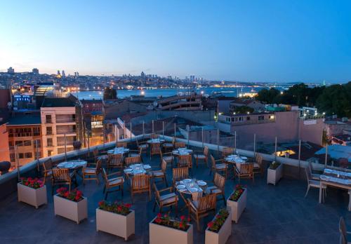 伊斯坦布尔伊斯坦布尔 - 锡尔凯吉希尔顿逸林酒店的享有带桌椅的屋顶露台的景致。