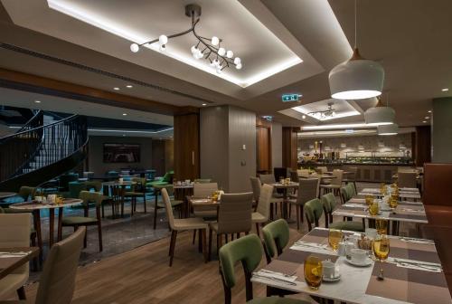 伊斯坦布尔伊斯坦布尔 - 锡尔凯吉希尔顿逸林酒店的一间带桌椅的餐厅和一间酒吧