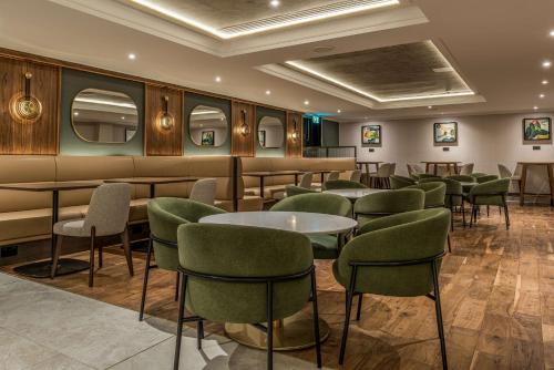 沃特福德Hilton London Watford的一间餐厅,房间内设有绿色的椅子和桌子