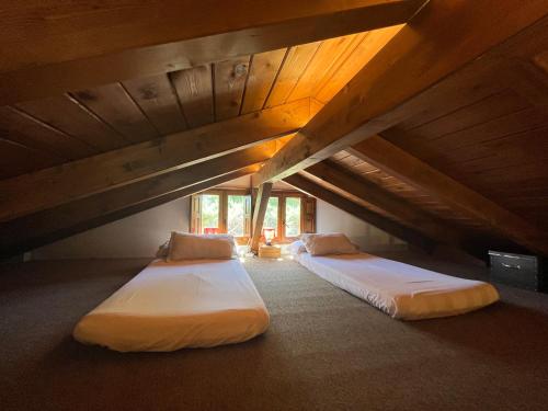 马塔埃尔皮诺Acogedora casa rural en la sierra de Madrid的阁楼间设有两张床铺和木制天花板