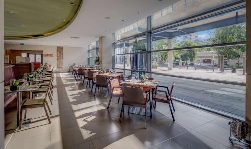 伦敦希尔顿伦敦金丝雀码头酒店的餐厅设有桌椅和大窗户。