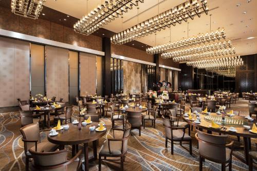 广州广州天河希尔顿酒店 - 免费广交会穿梭巴士 - 采购商办证点的餐厅设有桌椅和吊灯。