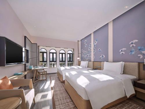 英德英德奥园希尔顿逸林度假酒店的一间酒店客房,设有三张床和一台平面电视