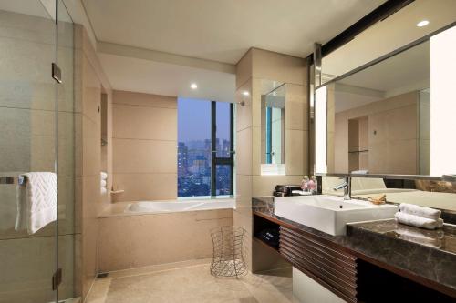 重庆重庆江北希尔顿逸林酒店的一间带水槽、浴缸和镜子的浴室