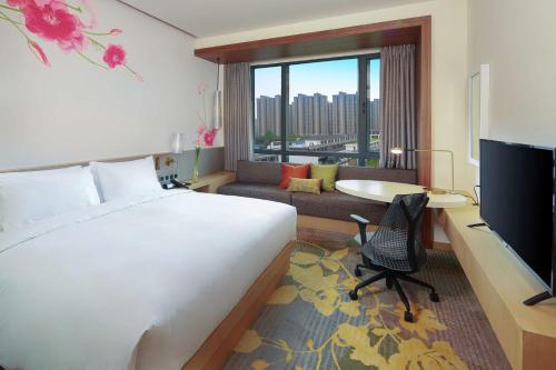 启东启东希尔顿花园酒店的酒店客房配有一张床、一张书桌和一台电视。