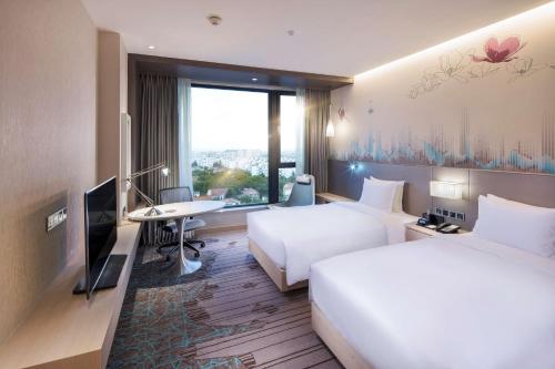 上海上海新虹桥国家会展中心灿辉希尔顿花园酒店的酒店客房设有两张床、一张桌子和一台电视。