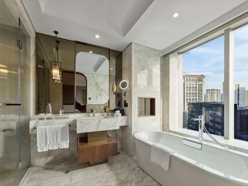 上海上海虹桥祥源希尔顿酒店的一间带两个盥洗盆、浴缸和窗户的浴室