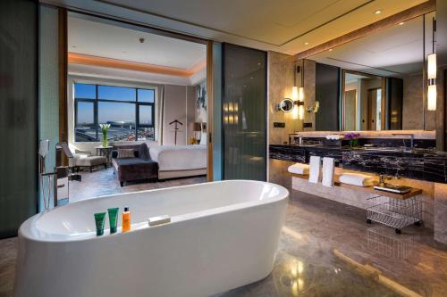 乌鲁木齐乌鲁木齐希尔顿酒店的带浴缸的浴室和客厅。