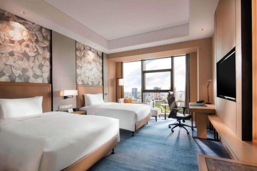 扬州扬州三盛希尔顿逸林酒店的酒店客房设有两张床和电视。
