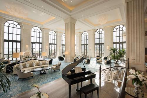 海口海口鲁能希尔顿酒店（亲子娱乐+沙滩+旅拍）的一个带钢琴的大客厅和一个带窗户的客厅