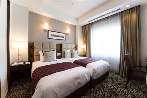 米子市米子市全日空皇冠假日酒店的酒店客房设有两张床和窗户。