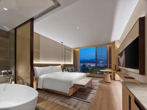 延庆县北京八达岭希尔顿逸林酒店的酒店客房设有一张大床和一个浴缸。