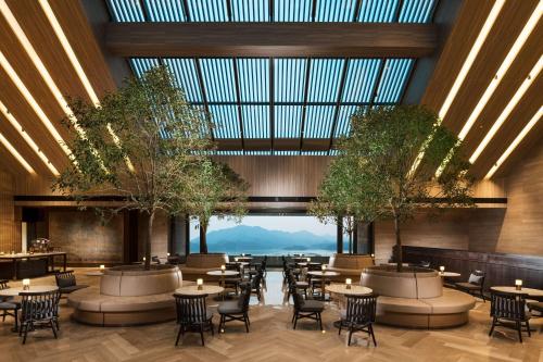 印渚杭州桐庐康莱德酒店的餐厅设有桌椅和大型玻璃天花板。
