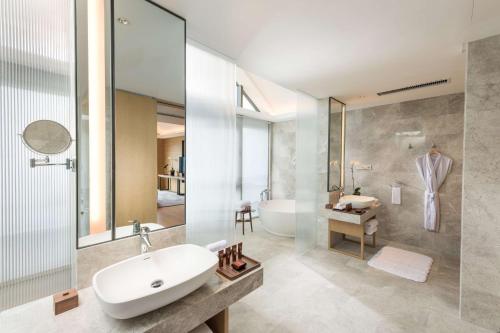 印渚杭州桐庐康莱德酒店的浴室配有白色水槽和浴缸。