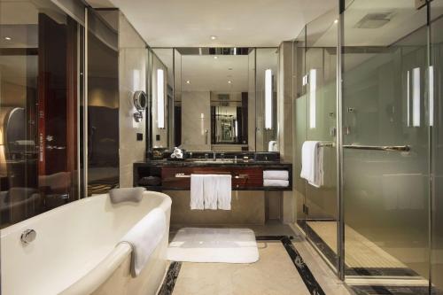 佛山佛山希尔顿酒店的带浴缸和玻璃淋浴间的浴室。