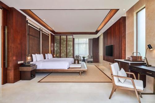 九江中海庐山西海希尔顿格芮精选酒店的一间卧室配有一张床、一张书桌和一台电视