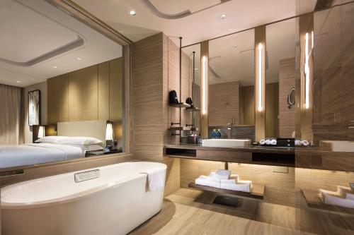 济南济南鲁能希尔顿酒店及公寓 的一间带床、浴缸和水槽的浴室