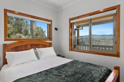上哈特Remutaka retreat的一间卧室设有一张床和两个窗户。