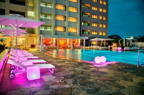 科伦坡科伦坡希尔顿酒店式公寓的一座带椅子和遮阳伞的游泳池位于一座建筑旁边