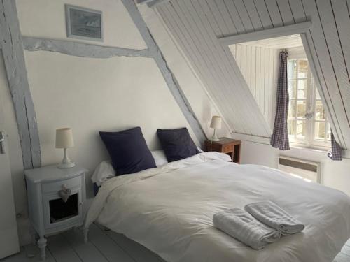 埃特勒塔La Petite Fanny的卧室配有带蓝色枕头的大型白色床