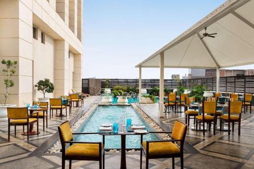 斋浦尔斋浦尔希尔顿酒店的酒店庭院设有游泳池和桌椅