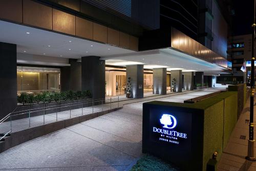 新山DoubleTree by Hilton Johor Bahru的一座建筑,在晚上前有标志