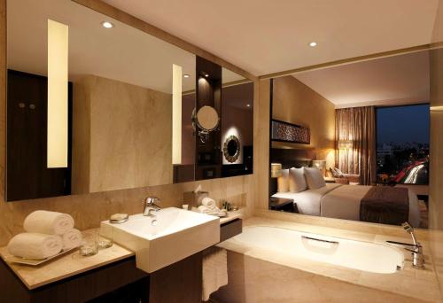斋浦尔斋浦尔希尔顿酒店的一间带水槽、床和镜子的浴室