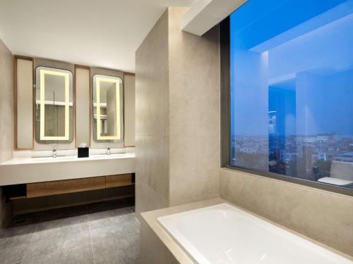 雅加达Hilton Garden Inn Jakarta Taman Palem的一间带两个盥洗盆的浴室和一个大窗户