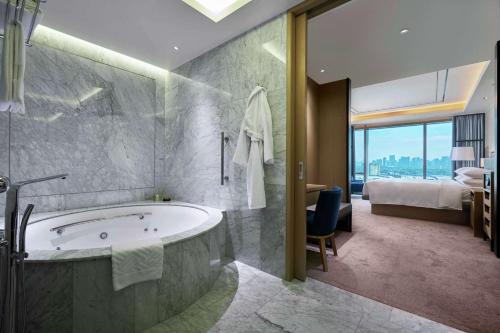 马尼拉Hilton Manila的带浴缸的浴室和1间带1张床的卧室