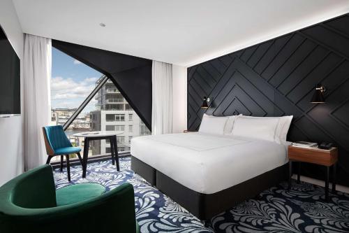 悉尼悉尼西部古玩系列希尔顿酒店的一间卧室配有一张床、一张桌子和一把椅子