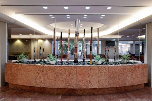 达尔文达尔文滨海希尔顿逸林酒店的大堂设有植物和蜡烛台