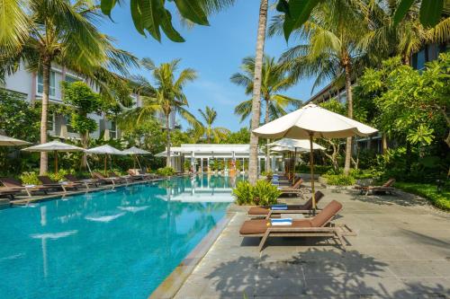 库塔巴厘岛机场希尔顿花园酒店的度假酒店的游泳池配有躺椅和遮阳伞