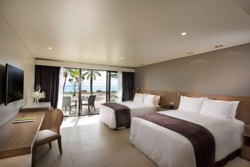 南迪希尔顿斐济酒店 - 索奈萨利岛的酒店客房设有两张床、一张桌子和一台电视。