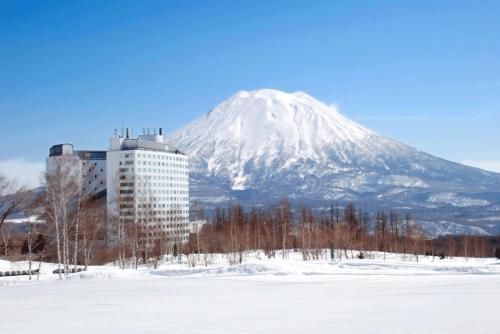 二世古北海道新雪谷希尔顿度假酒店的山前有一座建筑,上面有雪覆盖