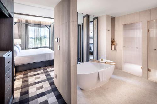 奥克兰Doubletree By Hilton Karaka的带浴缸的浴室和1间带1张床的卧室