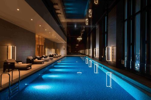 大阪大阪康莱德酒店的一座大型游泳池,位于酒店,设有沙发和椅子