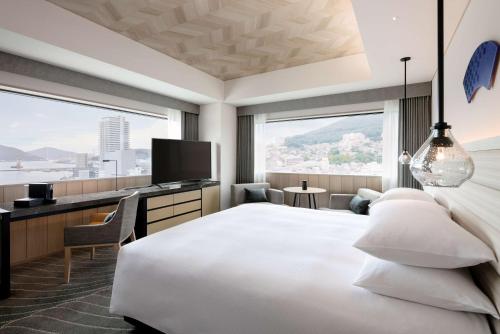 长崎Hilton Nagasaki的酒店客房配有一张床和一张书桌及一台电视
