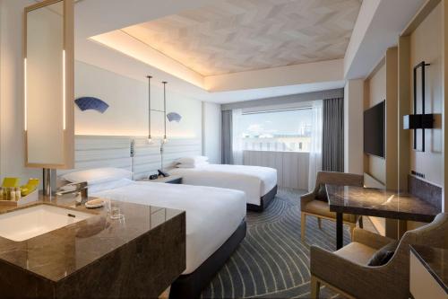 长崎Hilton Nagasaki的酒店客房配有两张床和一张书桌