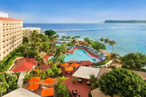 塔穆宁关岛希尔顿spa度假酒店的享有带游泳池和海洋的度假村的空中景致