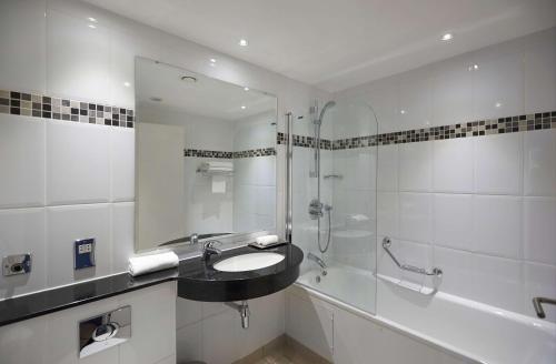 布里斯托北布里斯托尔希尔顿逸林酒店的白色的浴室设有水槽和淋浴。