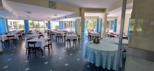 圣费利切-奇尔切奥Hotel Le Pleiadi的餐厅设有白色的桌椅和窗户。
