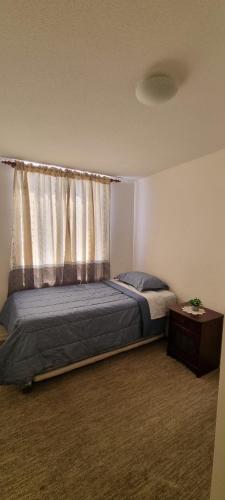 阿里卡Departamento por Dia en Condominio的一间卧室配有一张带窗帘和桌子的床