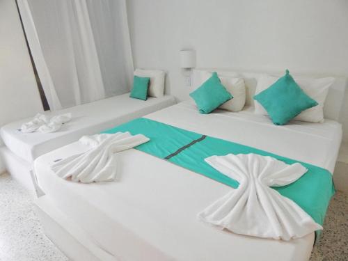 El YaquePOSADA RANCHO DELFIN的配有两张床铺的绿色和白色枕头