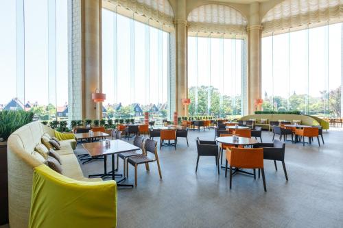 佐世保JR豪斯登堡大仓酒店的餐厅设有桌椅和大窗户。
