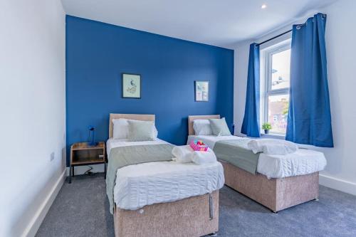 福克斯通Charming 3 BR in Folkestone!的一间卧室设有两张床和蓝色的墙壁