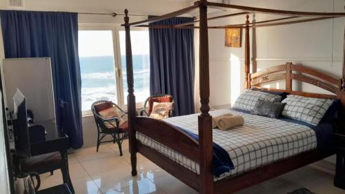 乌姆科马斯Umkomaas Lodge的一间卧室设有一张天蓬床,享有海景