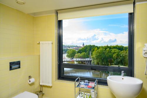 塔尔图Dorpat Hotel的一间带水槽的浴室和一个美景窗户